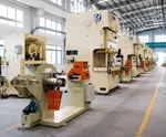 Industrial press machines arranged in a production hall, showing large-scale metal forming equipment for aluminum manufacturing.